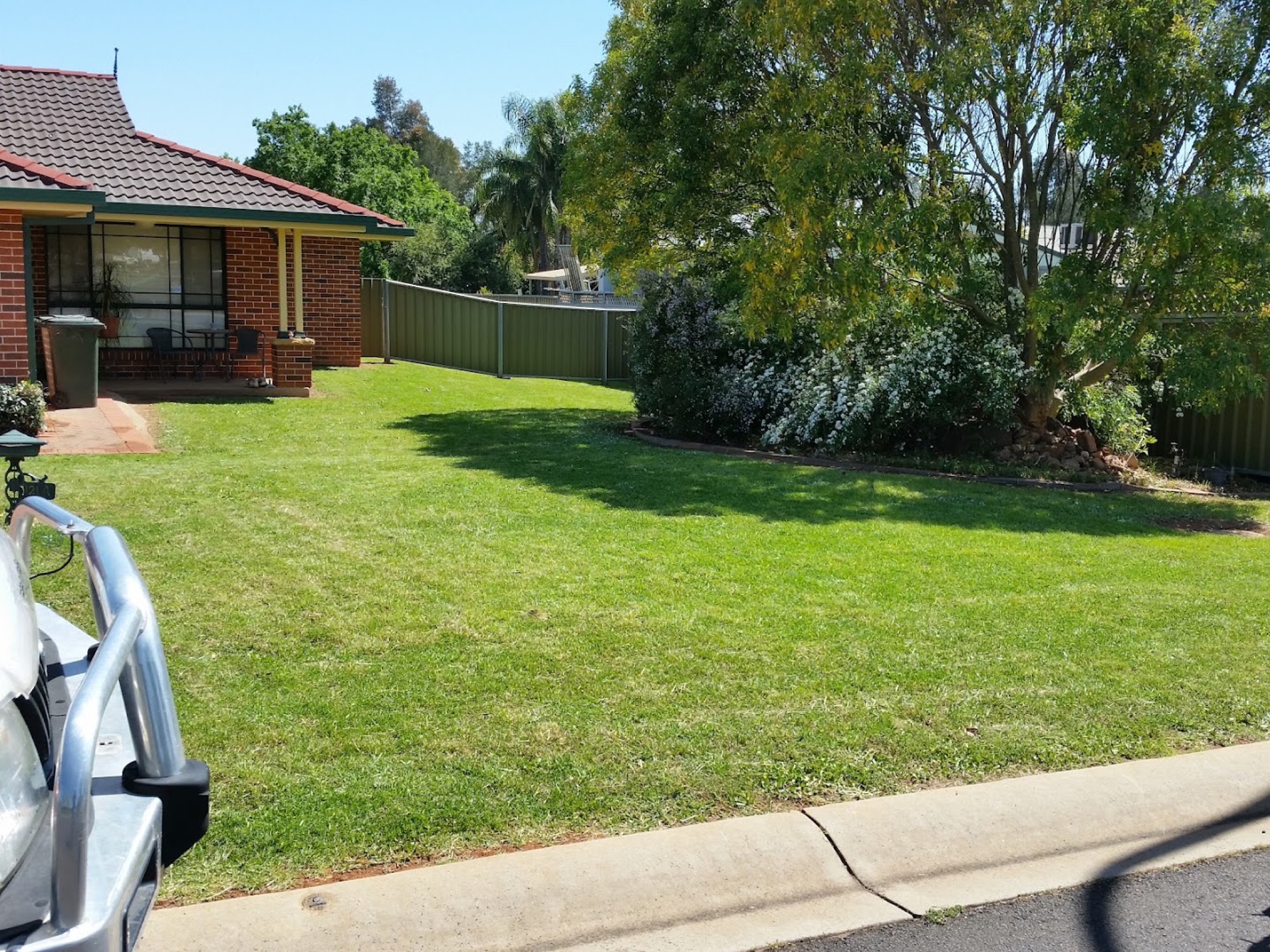 A mown front lawn running down to the kerb at a brick home in Dubbo