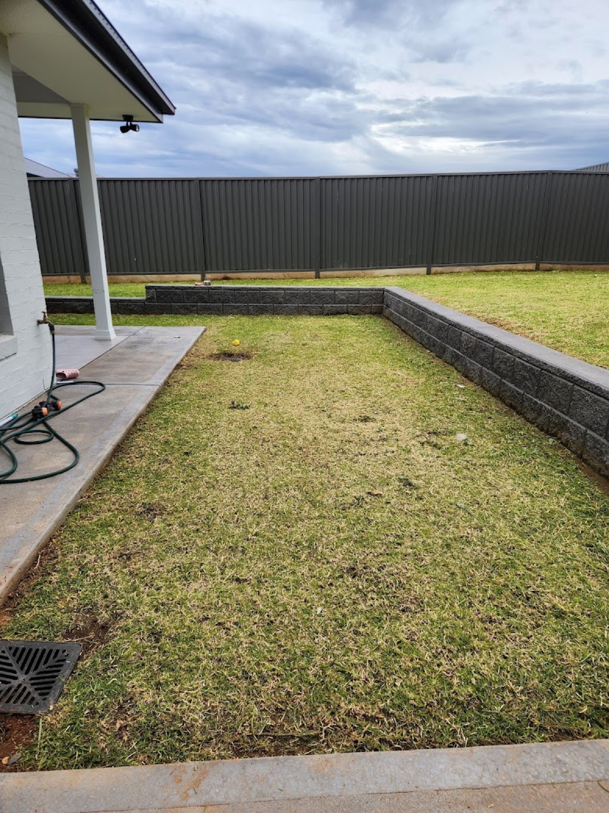 A back lawn mown level against a rendered retaining wall at a Dubbo house
