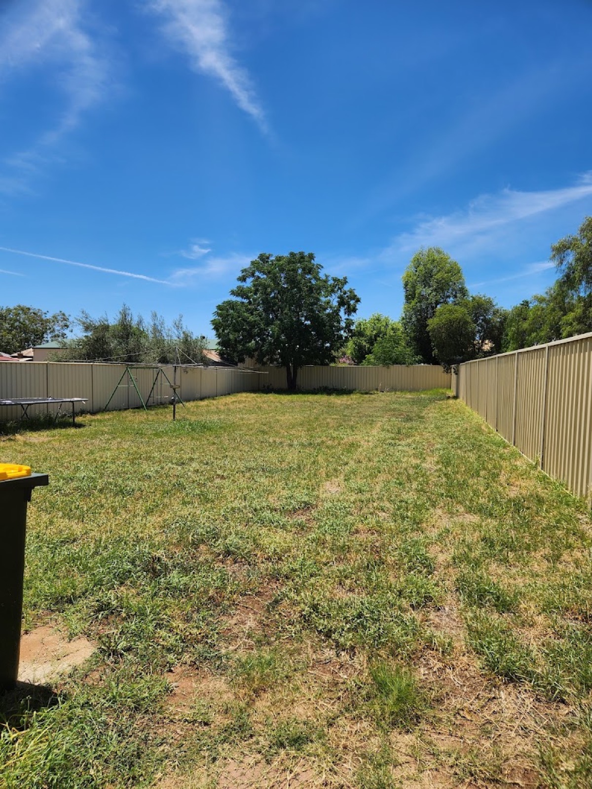 A large open residential block mown clear inside a Colorbond boundary fence