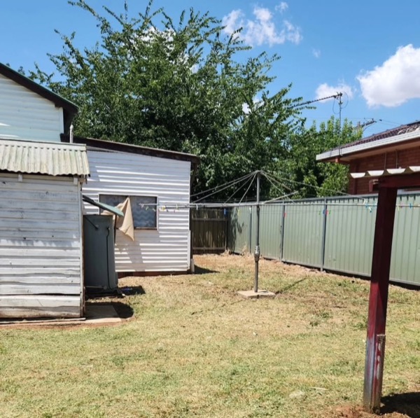 A back yard mown out around a shed and a clothesline