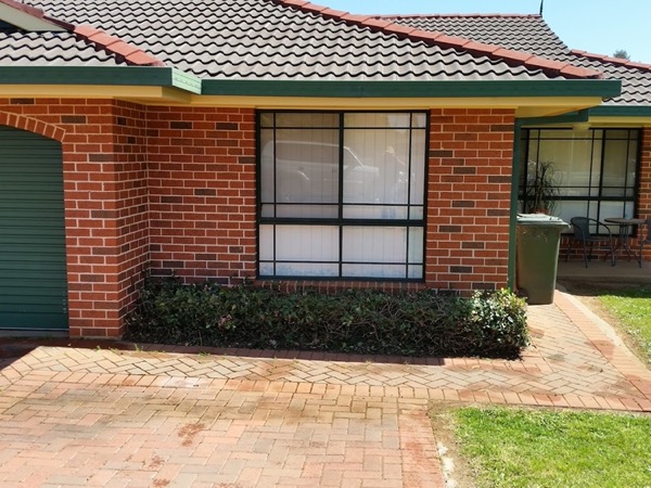 A brick home frontage with a brick driveway and trimmed lawn edges
