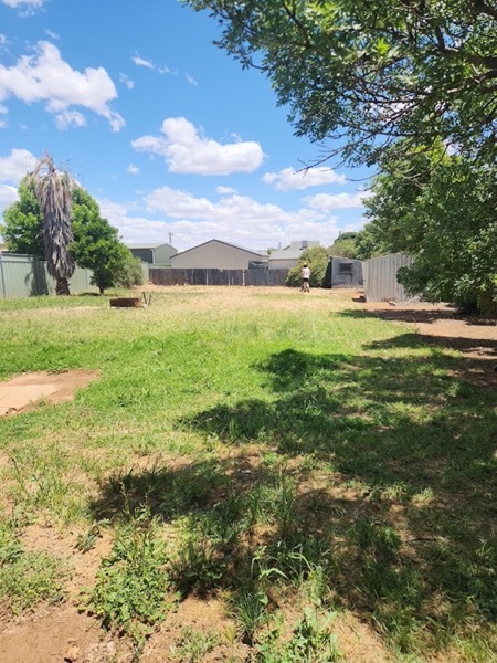 A wide front yard mown down with bare patches through the grass