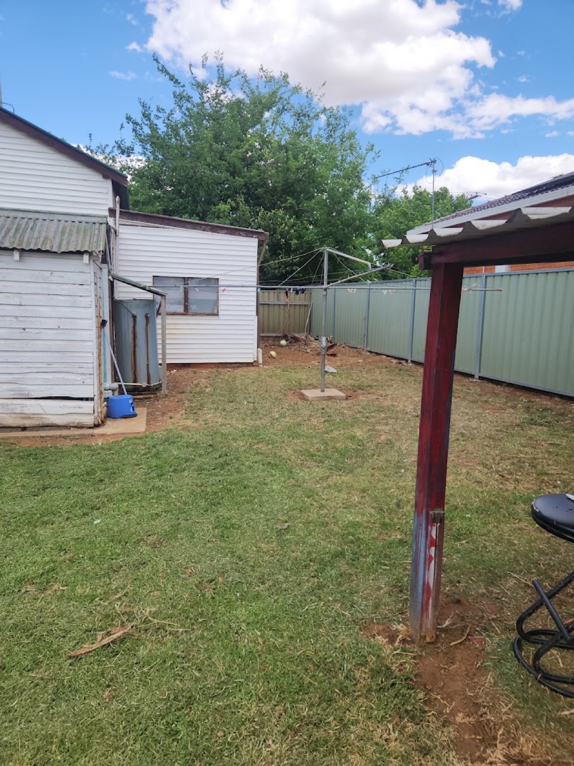 A back yard mown around a clothesline and a garden shed